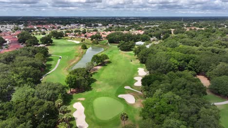 Aerial-approaching-shot-of-American-golf-course-with-river-and-suburb-neighborhood