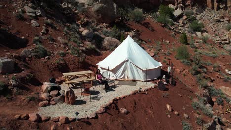 Toma-De-Drone-De-Una-Joven-Saliendo-De-Una-Tienda-De-Campaña-Yurta-Y-Disfrutando-Del-Paisaje-Del-Parque-Nacional-Zion,-Utah,-EE.UU.