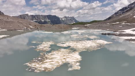 Hovering-above-the-waters-of-Gletschersee-at-Klausenpass,-Urner-Boden,-Schweiz,-highlighting-Klausenpass-and-the-glacial-lake-Griesslisee