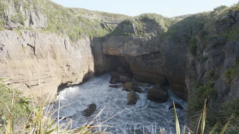 Waves-crashing-against-rock-formations-on-a-sunny-summer-day-at-Punakaiki-Pancake-Rocks,-West-Coast,-New-Zealand