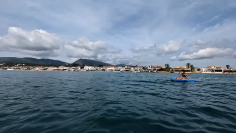 White-woman-on-the-wavy-water,-sitting-on-a-paddle-board,-enjoying-the-wide-cloudy-view-in-the-horizon,-slow-motion-and-copy-space