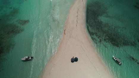 Una-Playa-De-Arena-Con-Barcos-Y-Sombrillas-En-Un-Día-Soleado,-Vista-Aérea