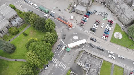 Aerial-view-of-a-UK-police-car-assisting-a-crashed-lorry,-with-traffic-building-up-around-the-scene