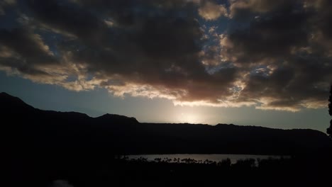 Very-slow-lowering-drone-view-of-Hanalei-Bay-at-sunset-with-clouds-in-Kauai,-Hawaii