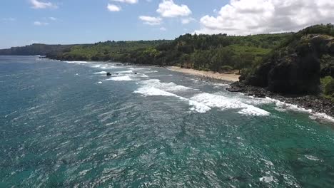 Flying-backward-away-from-the-rocky-beach-on-Maui,-Hawaii-on-a-sunny-day,-reverse-dolly