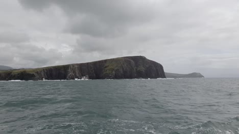 Moving-out-to-into-the-Irish-sea-off-the-coast-of-Kerry,-land-to-the-left-and-a-boat-to-the-right