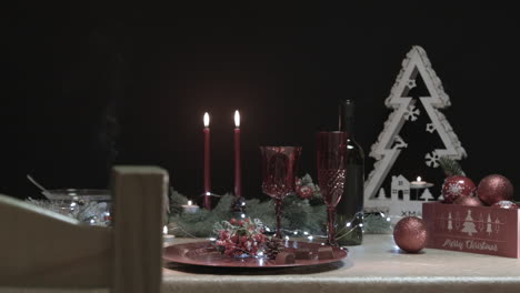 The-man-steals-two-chocolates-from-a-decorated-Christmas-table-in-a-dark-room-with-a-chair-in-foreground