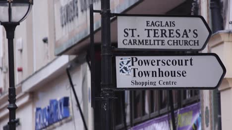 Tilt-shot-between-clock-and-powerscourt-townhouse-sign-in-Dublin,-Ireland