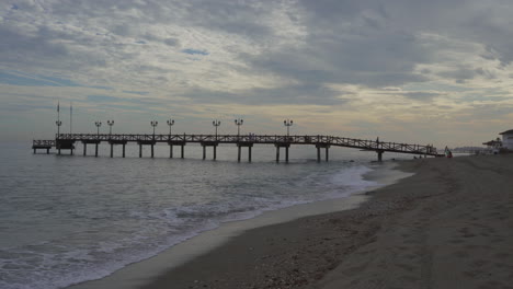 Marbella-wooden-pier-on-cloudy-over-cast-day,-dramatic-view-of-spanish-coast-line
