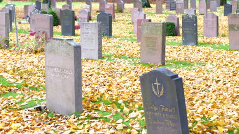 Scattered-leaves-together-with-the-tombstone-in-Kviberg-Cemetery,-Gothenburg,-Sweden