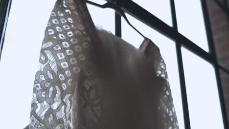 Slow-Motion-of-a-Brides-White-Wedding-Dress-Hanging-on-a-Window