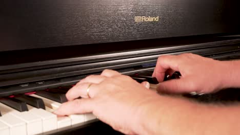 Close-up-of-a-married-old-man-playing-at-a-black-roland-piano