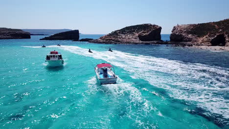 Drohne-Verfolgt-Boote-Und-Jetski-Fahrer-Auf-Kristallklarem,-Türkisfarbenem-Wasser-Auf-Der-Insel-Comino-In-Malta