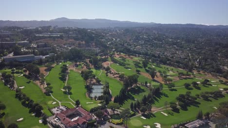 Aerial-drone-footage-of-golf-grounds-and-tennis-court-mountains-in-background-flying-forward