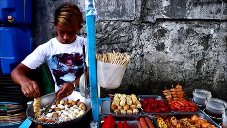 ANTIPOLO-CITY,-PHILIPPINES-–-JULY-12,-2019:-A-street-food-vendor-deep-fries-fish-balls-at-his-food-cart-and-sells-them-to-passers-by