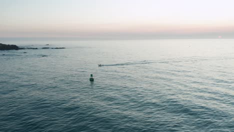 Aerial-tracking-of-a-small-boat-as-the-sun-sets-in-the-background