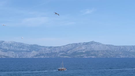 Schiff-Im-Ruhigen-Blauen-Meer-Und-Ein-Schwarm-Möwen,-Die-An-Einem-Schönen-Sonnigen-Tag-Darüber-Fliegen