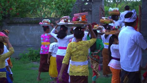 Toma-En-Cámara-Lenta-De-Un-Grupo-De-Mujeres-Y-Jóvenes-Llevando-Ofrendas-Hindúes-En-La-Cabeza-Al-Salir-De-Un-Templo-Hindú-Después-De-Una-Ceremonia-Vecinal.