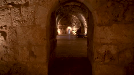 Un-Largo-Sótano-Con-Luz-Dorada-Proyectada-En-Las-Paredes-De-Piedra-Y-Un-Alto-Techo-De-Arco-En-Las-Ruinas-Del-Castillo-De-Kerak