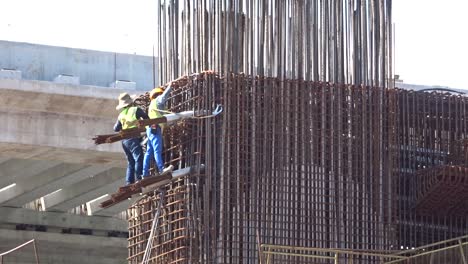 Trabajadores-De-La-Construcción-Que-Trabajan-En-Altura-Fabricando-Barras-De-Refuerzo-De-Acero-En-El-Sitio-De-Construcción