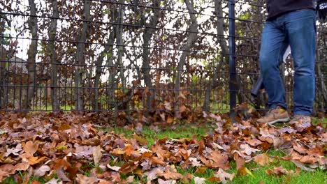 Worker-blowing-autumn-leaves-of-the-fence-in-slow-motion