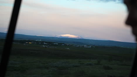 Icelandic-mountain-peak-in-background,-person-in-car-blurred-foreground