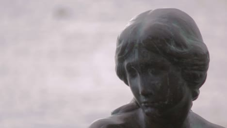 Close-up-of-the-head-statue-of-Little-Mermaid-in-Copenhagen,-Danmark-in-sunny-day-with-sea-on-the-background