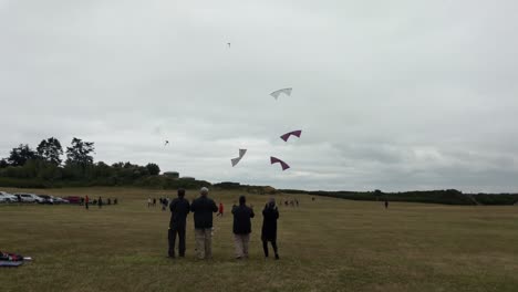 Four-people-flying-highly-maneuverable-stunt-kite-in-coordination-on-a-cloudy-windy-day-in-a-grass-field-at-Fort-Casey