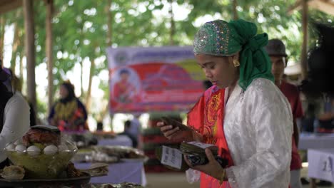 Pretty-woman-wearing-bright-ornately-decorated-clothing-smiles-and-laughs-as-she-places-cards-on-a-table-to-identify-food-for-guests