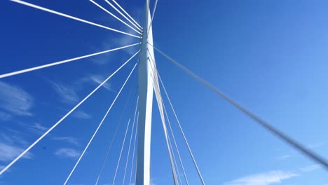 Driving-through-the-beautiful-white-architecture-suspension-bridge-of-Kanaleneiland,-Netherlands---Wide-rolling-shot