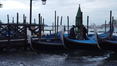 people-in-parked-gondola-in-ponte-san-marco-venice,-dolly-in-slow-motion-shot