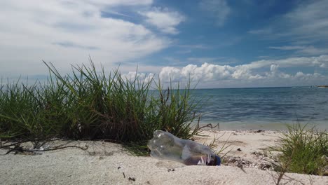 Weißer-Sand,-Strahlend-Blauer-Himmel-Und-Türkisfarbenes-Meer-Mit-Weggeworfener-Plastiktrinkflasche