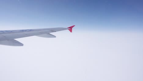 Plane`s-wing-on-a-partly-blue-and-white-sky-background