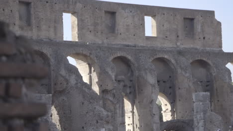 Slide-Reveal-of-Colosseum-Arches-From-Behind-Brick-Wall-in-Rome,-Italy