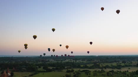 Diapositiva-Aérea-A-La-Izquierda-De-Globos-Aerostáticos-Volando-Sobre-Bagan,-Myanmar-Al-Amanecer.