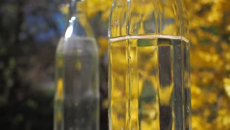 Glass-bottle-with-fresh-water-on-yellow,-floral-background