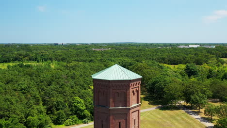 Dolly-Geschossen-Nach-Vorne-Direkt-über-Die-Spitze-Eines-Backstein-Wasserturm-An-Einem-Sonnigen-Tag-In-Einem-Ruhigen-Grünen-Feld