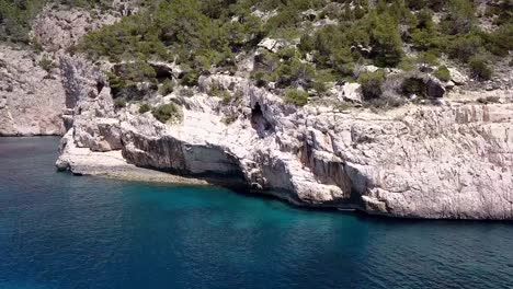 Drohnenaufnahme-Eines-Typen,-Der-Eine-Klippe-Auf-Ibiza-Erklimmt