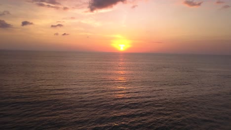 High-angle-drone-view-of-the-sunset-at-the-beach-in-Canggu,-Bali-Indonesia,-flying-backwards