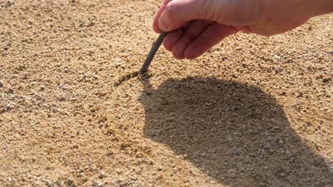 Drawing-heart-in-gold-sand