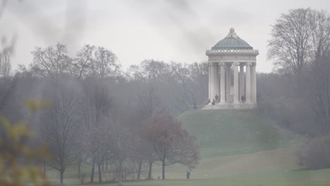 People-sit-and-walk-around-a-large-monument-in-a-park-in-Munich-Germany