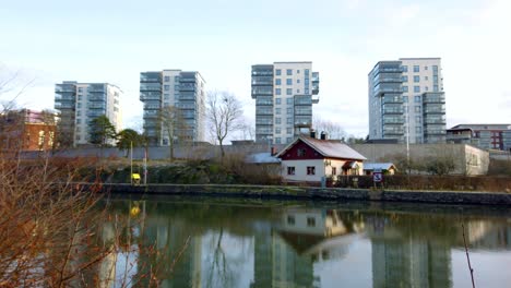 Beautiful-reflection-in-canal,-apartment-block-with-Scandinavian-Architecture,-red-and-white-villa,-Pan-Left