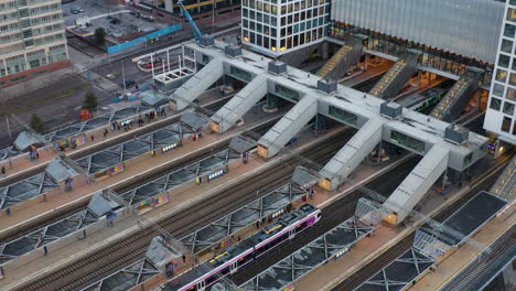 Aerial,-drone-shot-overlooking-trains-at-the-Pasila-railway-station,-the-Mall-of-Tripla,-on-a-cloudy-day,-in-Helsinki,-Finland