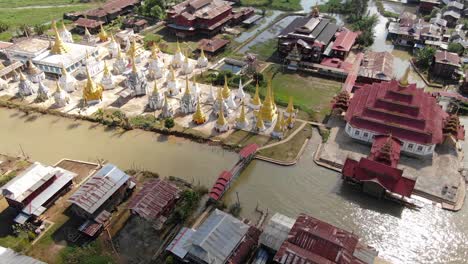 Boat-passing-by-a-Buddhist-Pagoda-at-a-village-on-Inle-Lake,-Myanmar