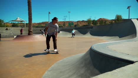 male-Skillful-Skateboarder-Riding-Skateboard-on-Edge-of-Skate-Park,-skateboarders-in-the-background,-Slow-Motion-on-a-clear-day