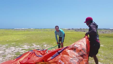 Man-with-leg-prosthesis-kitesurfer-inflates-kite-and-prepare-equipment-on-grass-beach