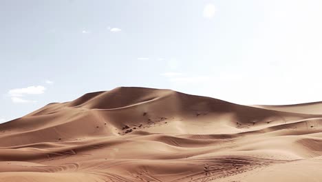 Zeitraffer-Von-Vorbeiziehenden-Wolken-Und-Sand,-Der-An-Einem-Sonnigen-Tag-Durch-Die-Wüste-In-Marokko-Geweht-Wird