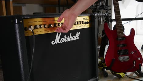 Hombre-Encendiendo-Y-Girando-Diales-En-Un-Amplificador-Marshall-De-100-Vatios,-Para-Tocar-La-Guitarra-Eléctrica