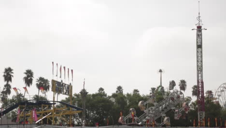 Rides-at-the-Fair-Ready-Before-Opening,-Palm-Trees-and-a-Cloudy-Gloomy-Sky