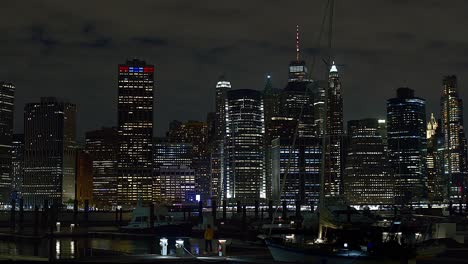 Brooklyn-Docks-Bei-Nacht-Mit-Der-Skyline-Von-New-York-Im-Hintergrund-Und-Im-Wasser-Vertäuten-Booten